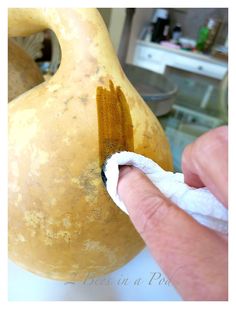 a hand holding a piece of cloth next to a vase