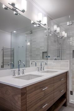 a bathroom with two sinks, mirrors and lights on the wall above them is shown