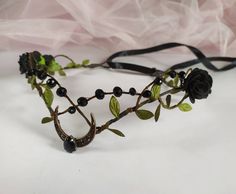 a headpiece made out of branches and flowers with beads on the sides, sitting on a white surface