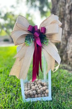 a bow on top of a box filled with rocks in the grass next to a tree