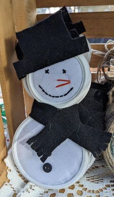 a snowman sitting on top of a wooden chair next to a basket filled with yarn