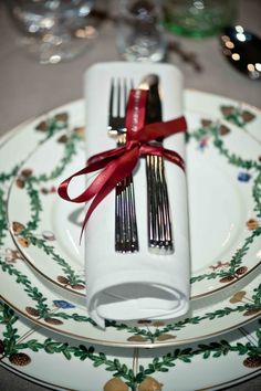 an image of a table setting with silverware and red ribbon on the napkins