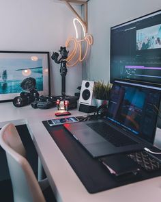 a laptop computer sitting on top of a white desk next to a monitor and speakers