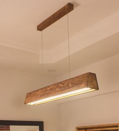 a wooden light fixture hanging from the ceiling above a bed in a room with white walls