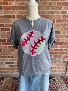 You can support all the baseball teams with this super blingy shirt! The ball is made with iridescent white sequins which will shift to a pinkish hue in the light. The laces are cut from faux velvet which gives them a raised look.  The design is done on a grey shirt with white paint splatter. You can choose to have the neckline cut, (similar to a vneck) or left as a crewneck.  This design is finished and ready to ship. Quantities listed are what we have in stock. If your size is sold out, we are happy to make another, however it wouldn't be a quick ship. If you would like this design in your team colors we would be happy to make you one. Just send us a message and colors you'd like.  For this design we used unisex gildan softsyle tshirts.  Because our items are handmade, there will be slig Short Sleeve Tops With Glitter Print For Game Day, Casual Game Day T-shirt With Glitter Print, Casual T-shirt With Glitter Print For Game Day, Casual Glitter Print T-shirt For Game Day, Casual T-shirt With Glitter Print For Sports Events, White Casual Sequined T-shirt, Casual White Sequin T-shirt, Casual Glitter Short Sleeve T-shirt, White Paint Splatter