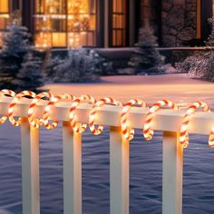 lighted candy canes on top of a fence in front of a house