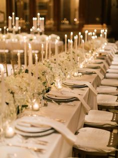 a long table is set with white flowers and candles