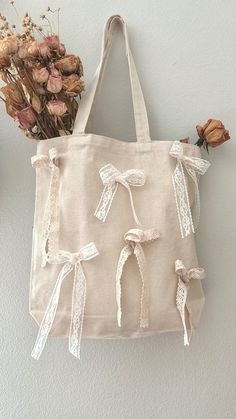 a tote bag hanging on the wall next to dried flowers and a vase with dried roses