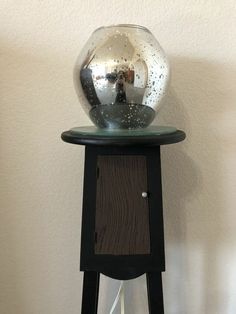 a glass ball on top of a wooden stand next to a white wall and floor