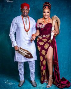 two people standing next to each other in front of a blue background wearing african clothing