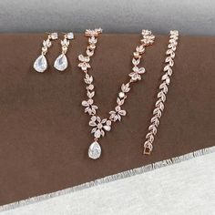 This Rose Gold Floral Bridal Jewelry Set is a perfect ensemble for the bride seeking a touch of boho charm on her special day. The set includes a chunky necklace, teardrop pendent choker, and a leaf bracelet, all adorned with sparkling cubic zirconia stones that catch the light beautifully. CZ NECKLACE: Necklace Length: approx 16 1/2 inches. Featuring a floral design that adds a touch of nature's elegance to your bridal look. Crafted with high-quality cubic zirconia stones and copper, this necklace is designed to sparkle under any light. CZ EARRINGS: These floral design earrings are a beautiful addition to the set, suitable for any occasion. The earring length is about 1 3/8" (3.5cm), with a bottom teardrop size of 1/2"H x 3/8"W (1.5cm x 1cm), offering a delicate balance of size and style. Wedding Jewelry Rose Gold, Bohemian Teardrop Jewelry For Wedding, Bohemian Teardrop Necklace For Weddings, Rose Gold Teardrop Jewelry Sets For Wedding, Rose Gold Teardrop Wedding Jewelry Sets, Bohemian Wedding Jewelry With Matching Earrings, Bohemian Wedding Necklace With Matching Earrings, Bohemian Jewelry Sets With Matching Earrings For Wedding, Bohemian Necklace With Matching Earrings For Wedding