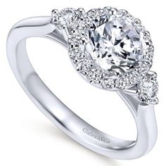 a white gold engagement ring with three diamonds on the band and an oval center stone