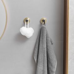 two towels hanging on the wall next to a towel rack with hooks and a heart shaped soap dispenser