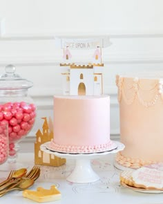 there is a pink cake and other desserts on the table with goldware in front of it