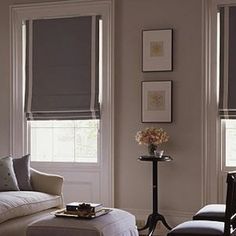 a living room filled with furniture and windows covered in roman blind shades on top of them