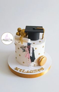 a graduation cake decorated with gold and white decorations, including a black cap on top