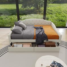 a bed sitting in the middle of a living room next to a large glass window