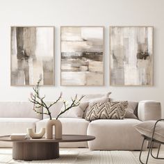 a living room with three paintings on the wall and a coffee table in front of it