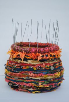 a stack of multicolored yarn with pins sticking out of the top and bottom