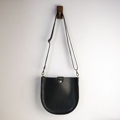 "With a classic saddle bag shape and convenient, magnetic snap closure, this is your new go-to bag. Easily fit everyday items including wallets, keys, phone, and more. We hand-cut buttery soft yet durable 5 oz Horween leather and stitch it with heavyweight nylon thread. The crossbody straps are available in multiple color options and are fitted with solid brass hardware. * Approximately 10\" x 10\" x 2\" * Crossbody strap drop adjusts from 16\" - 28\" * Magnetic snap closure * Unlined interior" Classic Saddle Bag With Adjustable Strap For On-the-go, Classic Crossbody Saddle Bag For On-the-go, Classic Saddle Bag With Removable Pouch For Daily Use, Versatile Shoulder Bag With Snap Closure For On-the-go, Modern Satchel Saddle Bag With Magnetic Closure, Rectangular Saddle Bag With Magnetic Closure For Daily Use, Satchel Flap Bag With Magnetic Closure, Modern Crossbody Saddle Bag With Magnetic Closure, Top Handle Satchel With Magnetic Closure For Everyday Use