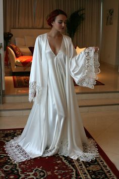 Cut off to receive in time for Christmas has passed. Any orders placed as of 11/26 are not guaranteed for Christmas delivery. Turnaround time is 4 weeks to ship from date ordered. The Isadora robe is a decadent rich off white pearl satin accented with beautiful crocheted Venise lace around the hem and wide angel sleeves. Shimmering satin glows on the outside and is just as delicious on the inside next to the skin for the utmost in luxury. It comes with a tie sash belt. Perfect for the bride who Wedding Nightgown, Wedding Sleepwear, Bridal Robe Lace, Satin Bridal Robe, Bridal Nightwear, Bridal Nightgown, Wedding Night Lingerie, Lace Bridal Robe, Wedding Kimono