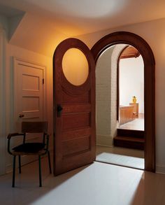 an open door leading to a bedroom with a chair in the corner and light coming through