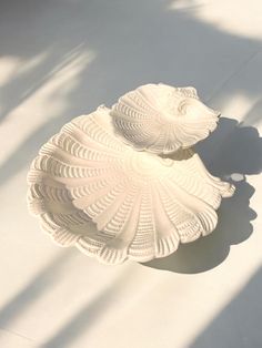 a white vase sitting on top of a table next to a shadow cast wallpaper