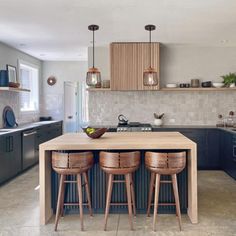 a kitchen with blue cabinets and wooden stools next to an island in the middle