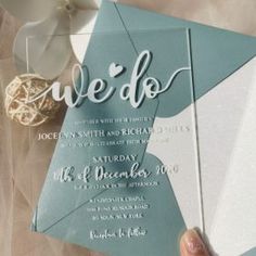 a person holding up a wedding card with the word wed written on it in silver foil