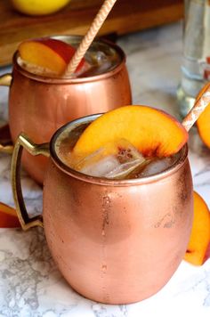 two copper mugs filled with ice and peaches