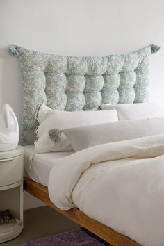 a bed with white sheets and pillows on top of it next to a night stand