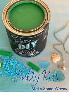 a can of green paint sitting on top of a table next to some sea glass