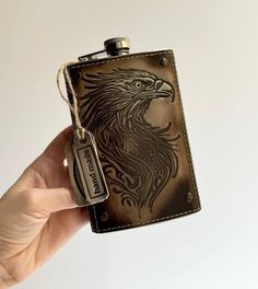 a hand holding a flask with an eagle on it