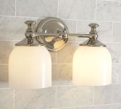 two light bathroom fixture with white glass shades in a marble tiled wall and floor area