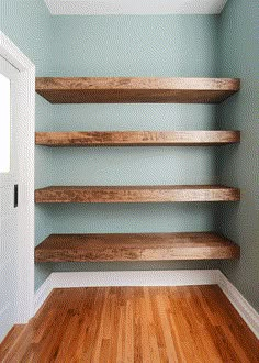 empty shelves in the corner of a room with wood flooring and blue wall paint