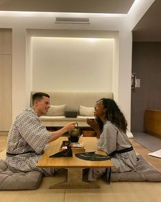 the man and woman are sitting on the floor having tea in front of each other