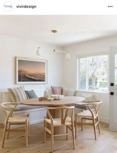 a dining room table with four chairs and a bench in front of a large window