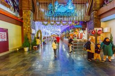 several people are walking through the lobby of a shopping mall with christmas decorations hanging from the ceiling