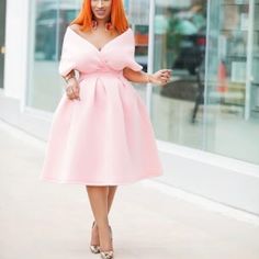 a woman in a pink dress is walking down the street with an orange hair and heels