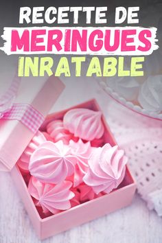 a box filled with pink meringues sitting on top of a white tablecloth