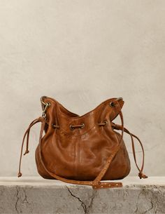 a brown leather purse sitting on top of a stone counter next to a white wall