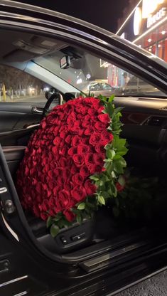 a large bouquet of red roses sits in the driver's seat of a car