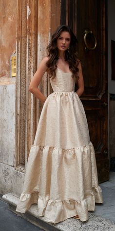 a woman standing in front of a door wearing a dress with tiered ruffles