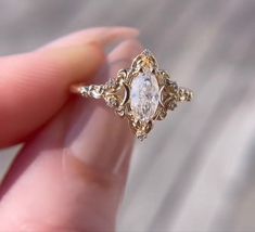 someone is holding an engagement ring with a diamond in it's center and filigrees on the sides