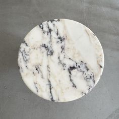 a marbled white and black plate sitting on top of a cement floor