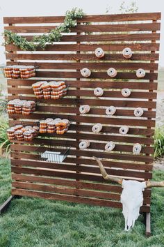 an outdoor display with donuts and cupcakes on wooden boards, in the grass