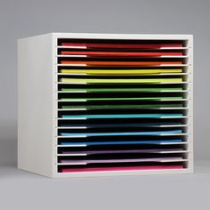 a multicolored stack of papers sitting on top of a white box