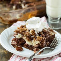 a piece of cake on a plate with whipped cream and pecans in the background