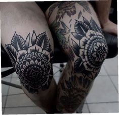 a man with tattoos on his legs is sitting in a chair and has flowers tattooed on his leg