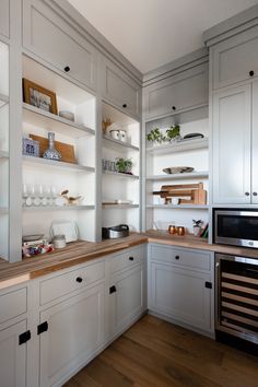 a kitchen with white cabinets and wooden counter tops, along with open shelving units